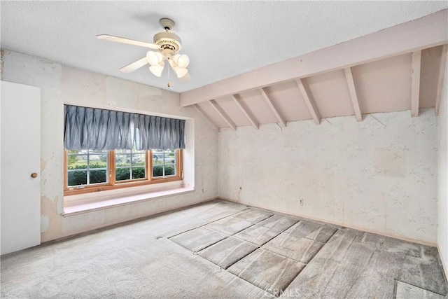 carpeted empty room with a textured ceiling, lofted ceiling with beams, and a ceiling fan