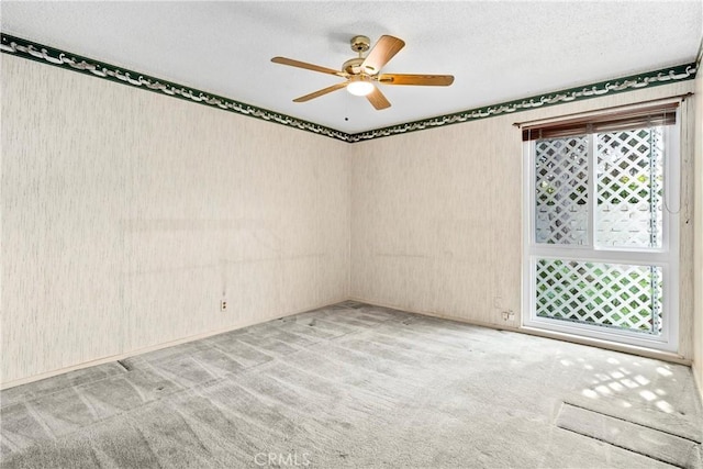 carpeted spare room featuring a textured ceiling and ceiling fan