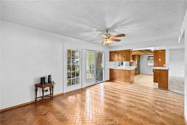 kitchen with brown cabinets, a textured ceiling, a peninsula, and ceiling fan