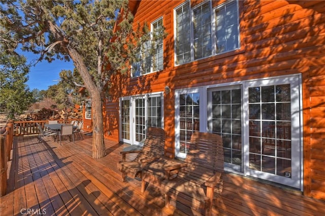 wooden terrace with outdoor dining space and french doors