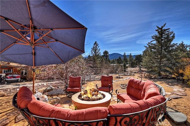 view of patio / terrace with a mountain view and an outdoor living space with a fire pit