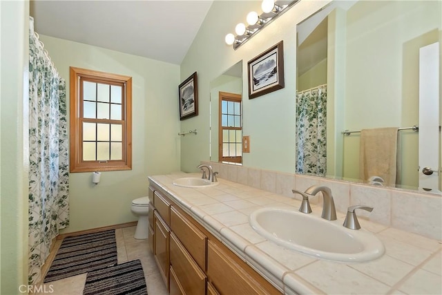 full bathroom with double vanity, a sink, toilet, and tile patterned floors