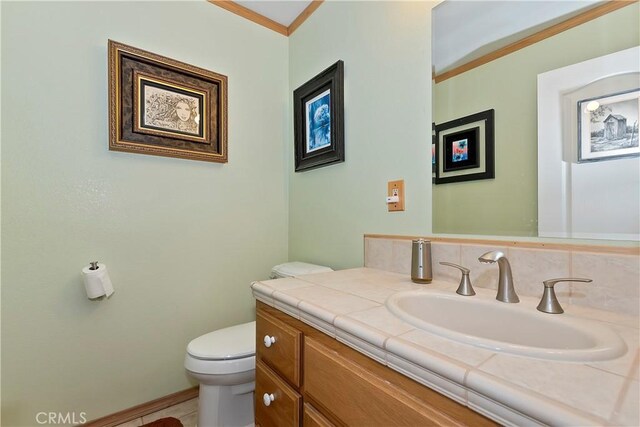 half bath featuring toilet, ornamental molding, and vanity