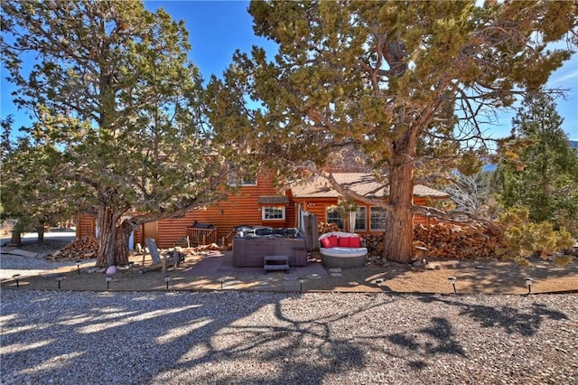 view of front of house featuring a patio, log veneer siding, and a hot tub