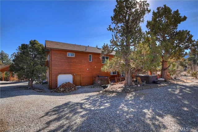 exterior space with a hot tub and an attached garage