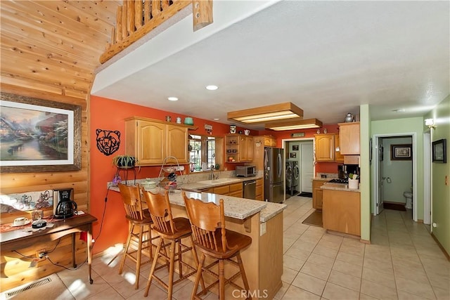 kitchen with visible vents, appliances with stainless steel finishes, a peninsula, a sink, and light tile patterned flooring