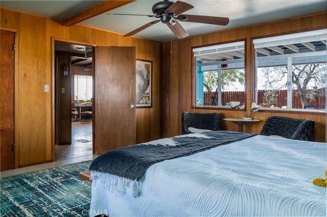 bedroom featuring multiple windows, wood walls, and beamed ceiling