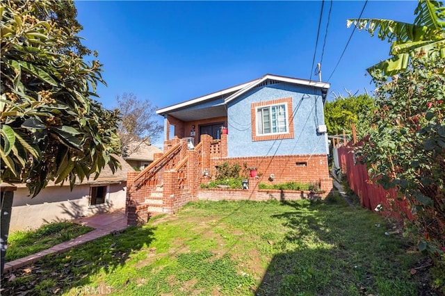 view of front of property with stairs, a front lawn, crawl space, and fence