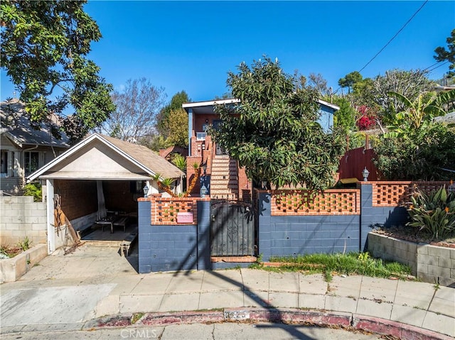 view of property hidden behind natural elements featuring a fenced front yard and a gate