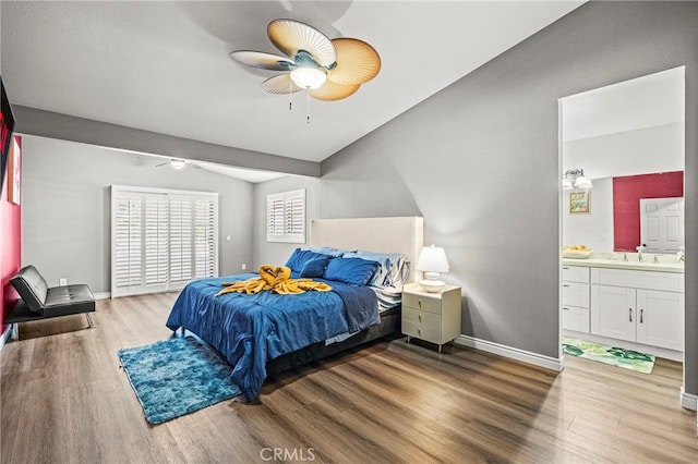 bedroom with lofted ceiling, ensuite bathroom, baseboards, and wood finished floors