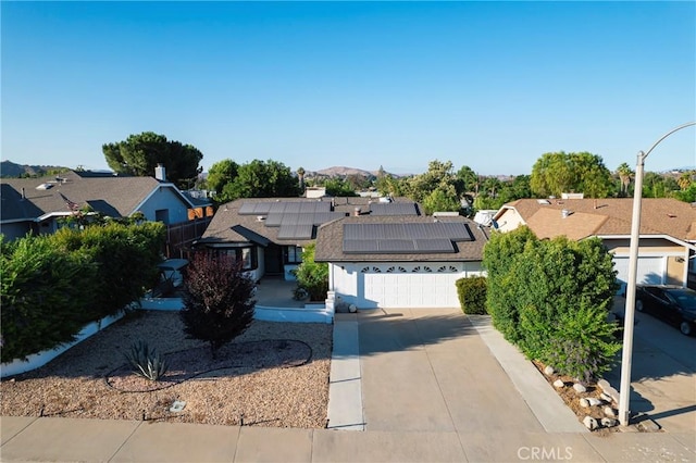 ranch-style home featuring a residential view, concrete driveway, an attached garage, and solar panels