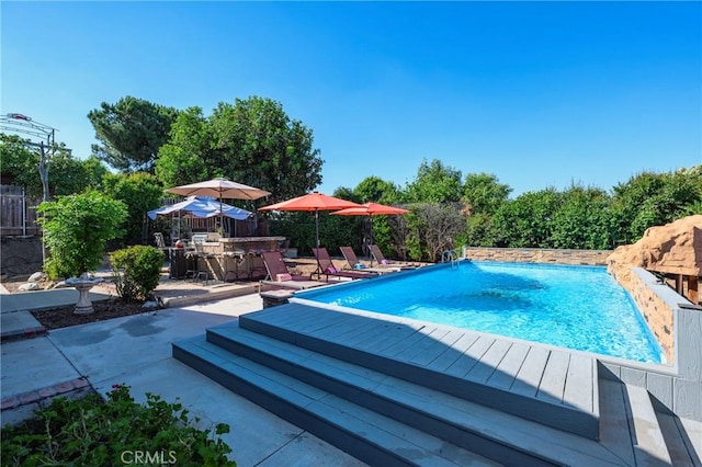 pool featuring a patio area, a fenced backyard, and outdoor dry bar