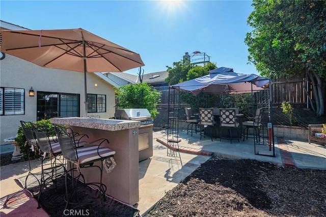 view of patio / terrace featuring area for grilling, outdoor dry bar, fence private yard, a grill, and outdoor dining space