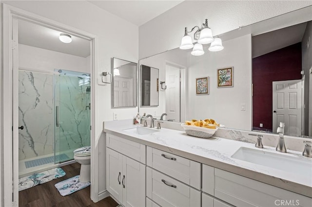 full bathroom featuring toilet, a marble finish shower, a sink, and wood finished floors