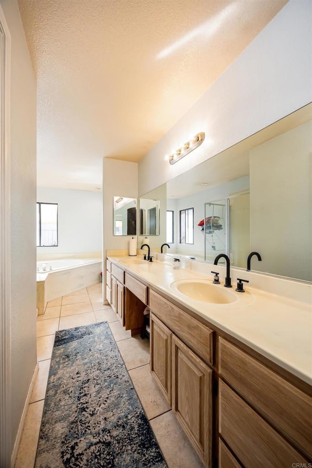 bathroom featuring tile patterned flooring, a sink, a bath, and a healthy amount of sunlight