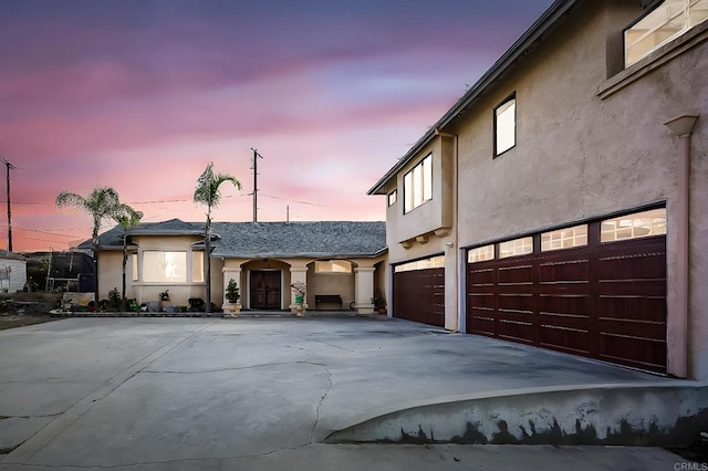 view of front of house with an attached garage, concrete driveway, and stucco siding