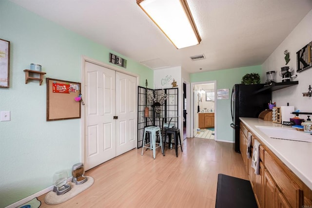 kitchen with visible vents, brown cabinets, light countertops, light wood-type flooring, and open shelves