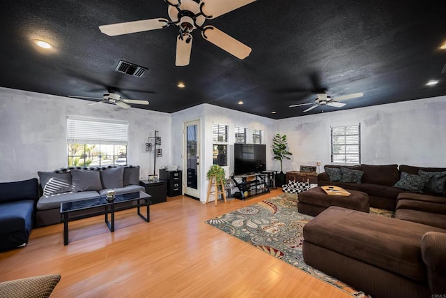 living room featuring a textured ceiling, visible vents, and wood finished floors