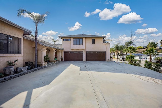 view of front facade featuring a garage, concrete driveway, and stucco siding