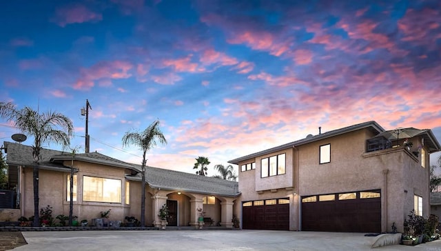 view of front facade with concrete driveway, an attached garage, and stucco siding