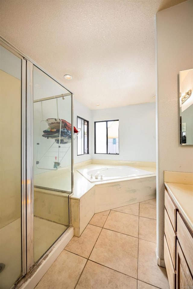 bathroom with tile patterned floors, a stall shower, a textured ceiling, vanity, and a bath