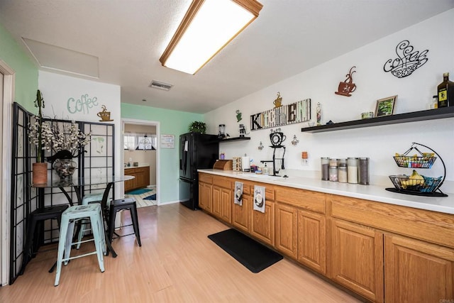 kitchen with open shelves, light countertops, visible vents, light wood-style floors, and freestanding refrigerator