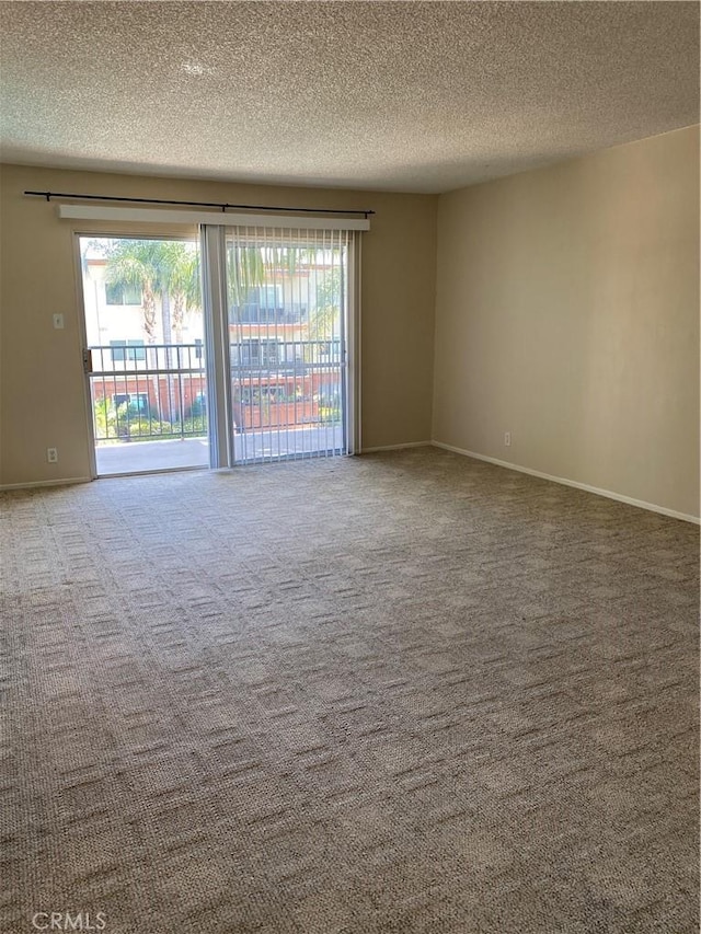 spare room featuring a textured ceiling, carpet floors, and baseboards