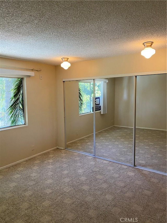 unfurnished bedroom with a textured ceiling, a closet, and carpet