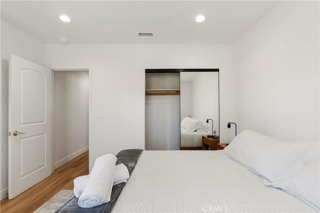 bedroom with a closet, visible vents, recessed lighting, and wood finished floors