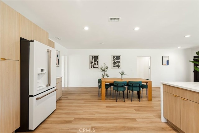 kitchen with visible vents, modern cabinets, light wood-style flooring, light brown cabinets, and white fridge with ice dispenser