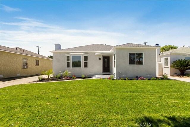 view of front of property featuring stucco siding, a chimney, and a front yard