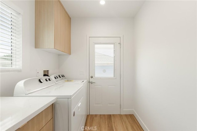 laundry area with light wood-type flooring, cabinet space, baseboards, and washing machine and clothes dryer