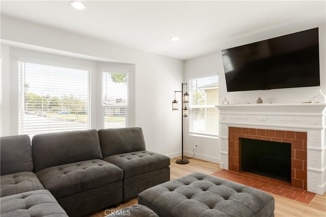 living room featuring recessed lighting, light wood-style flooring, a tile fireplace, and baseboards