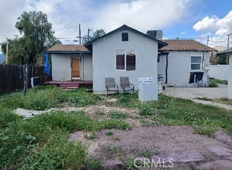 back of house featuring central AC, fence, and stucco siding