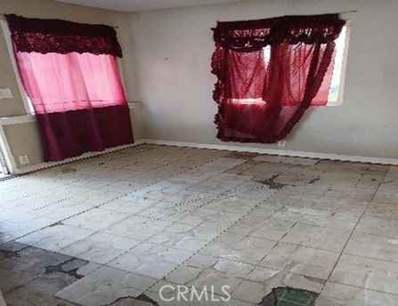 empty room with baseboards and tile patterned floors