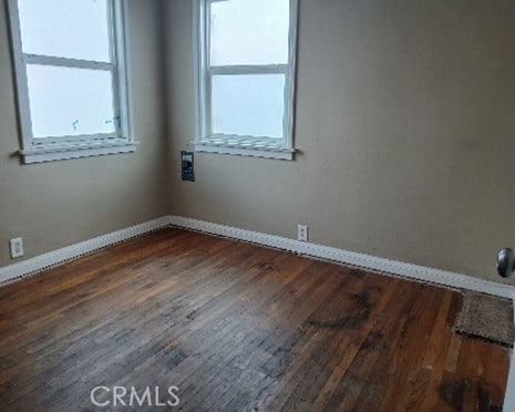 empty room featuring dark wood-style floors and baseboards