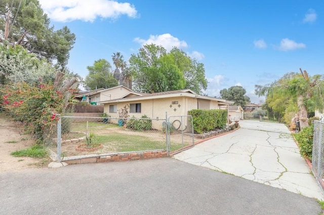 single story home featuring driveway, a fenced front yard, and stucco siding