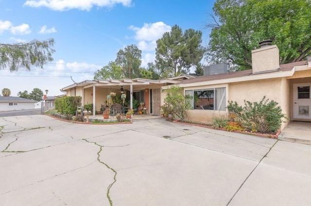 ranch-style home featuring a chimney and stucco siding