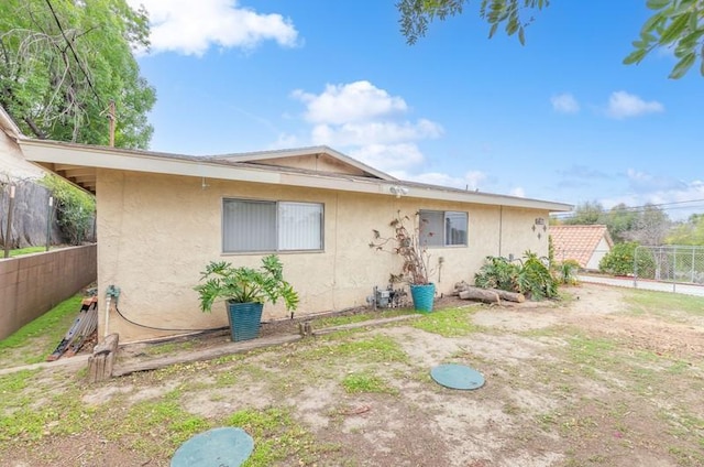 back of property featuring fence and stucco siding