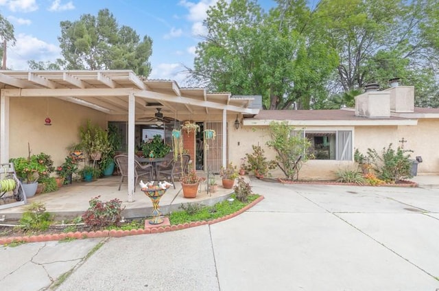 view of front of house featuring a chimney, a patio area, a ceiling fan, and stucco siding