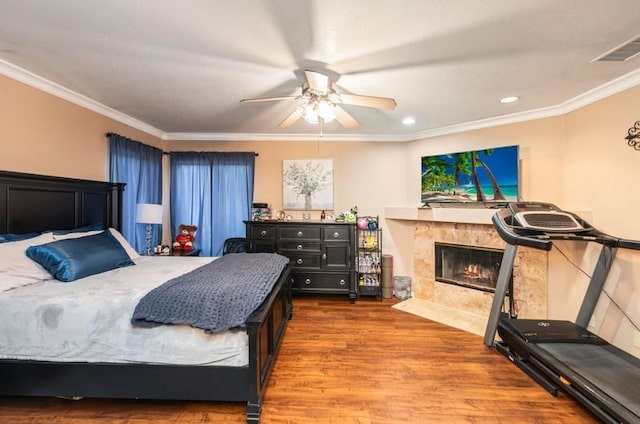 bedroom featuring a fireplace, recessed lighting, visible vents, ornamental molding, and wood finished floors