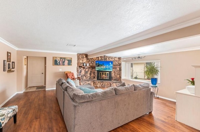 living area with a textured ceiling, a fireplace, wood finished floors, baseboards, and crown molding