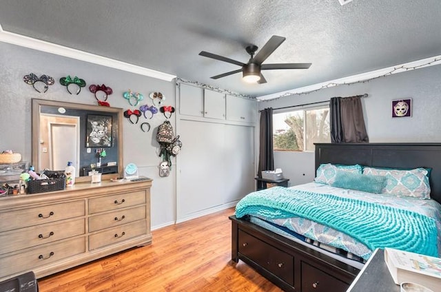 bedroom with light wood-style floors, crown molding, ceiling fan, and a textured ceiling