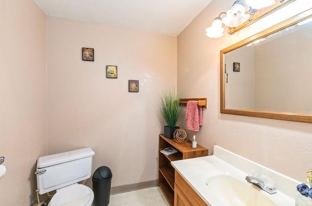 half bath with baseboards, vanity, and toilet