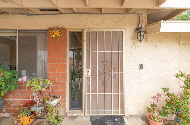 view of exterior entry featuring stucco siding and brick siding