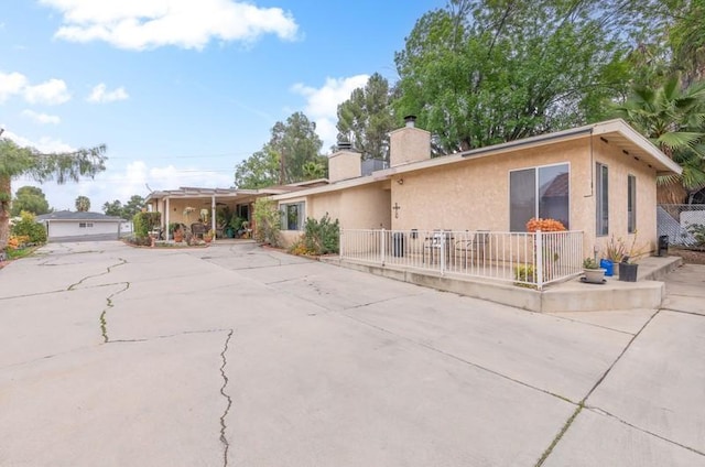 view of front of home featuring a patio, a chimney, fence, and stucco siding