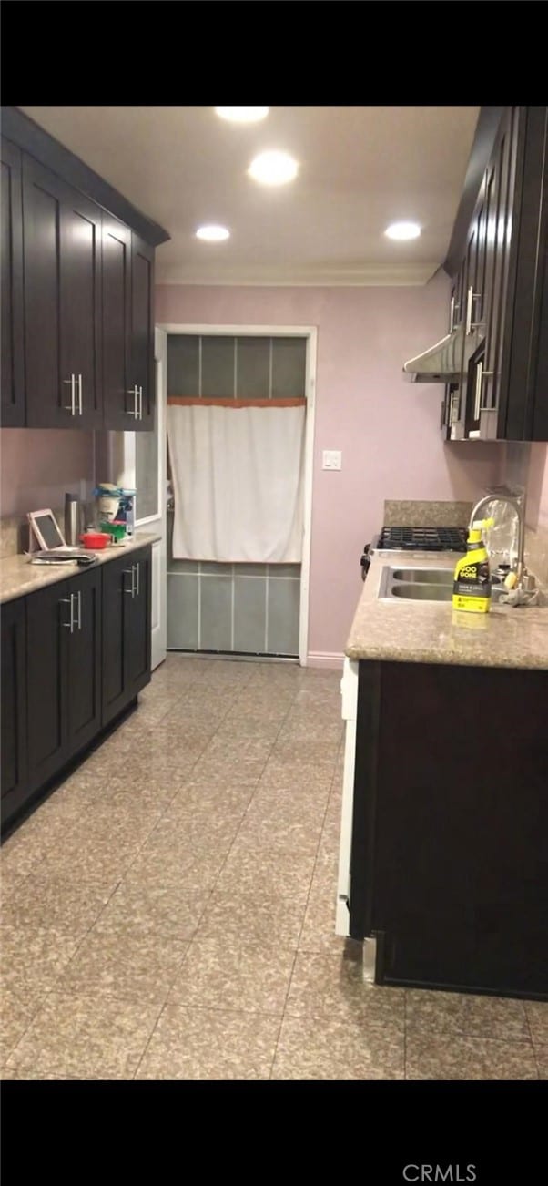 kitchen with light countertops, crown molding, and a sink