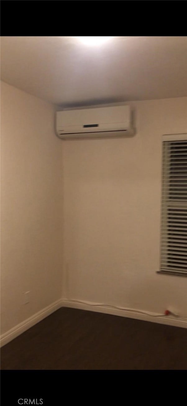 empty room featuring baseboards and an AC wall unit