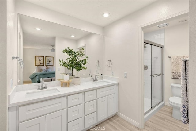 bathroom with connected bathroom, wood finished floors, toilet, and a sink