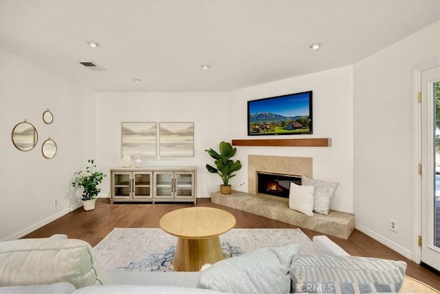 living room with visible vents, baseboards, wood finished floors, and a high end fireplace